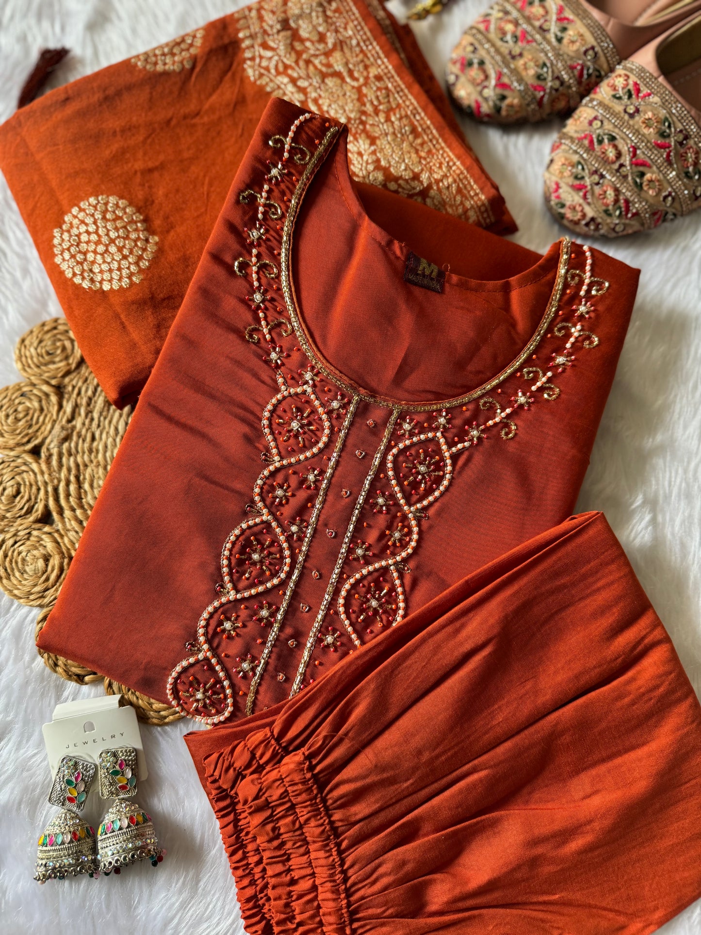 MD-176 This rust orange ethnic set, adorned with delicate embroidery and a touch of golden elegance, is your perfect pick for festive flair and timeless charm."