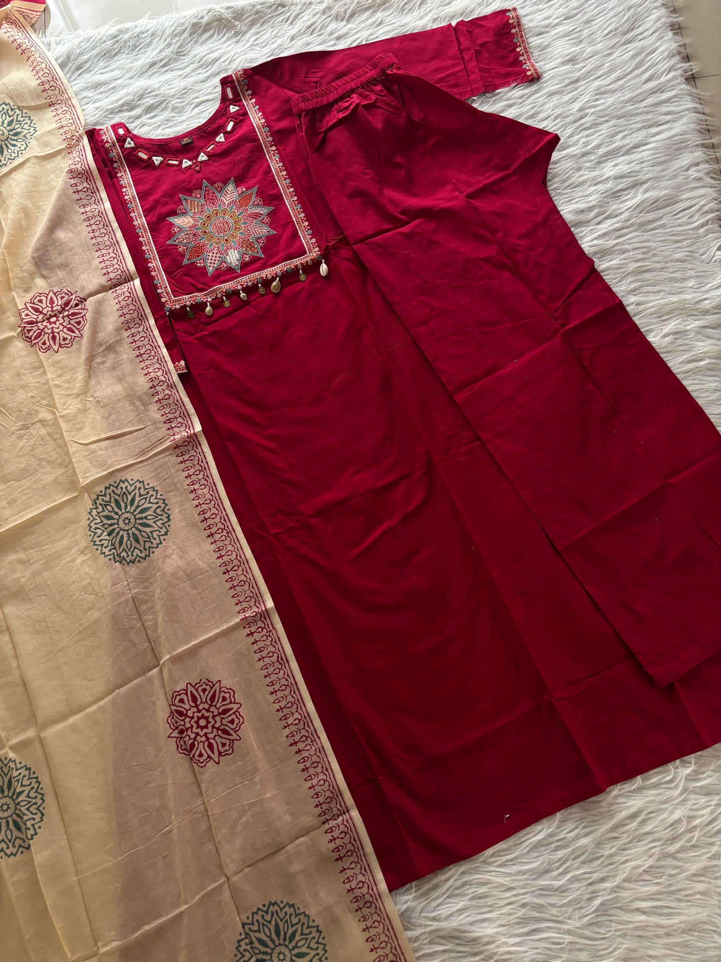 MD-265 This elegant three-piece ethnic set features a deep Kurti and matching trousers, paired with a contrasting cream-colored Dupatta. The ensemble balances rich, solid tones with intricate traditional detailing, making it ideal for festive
