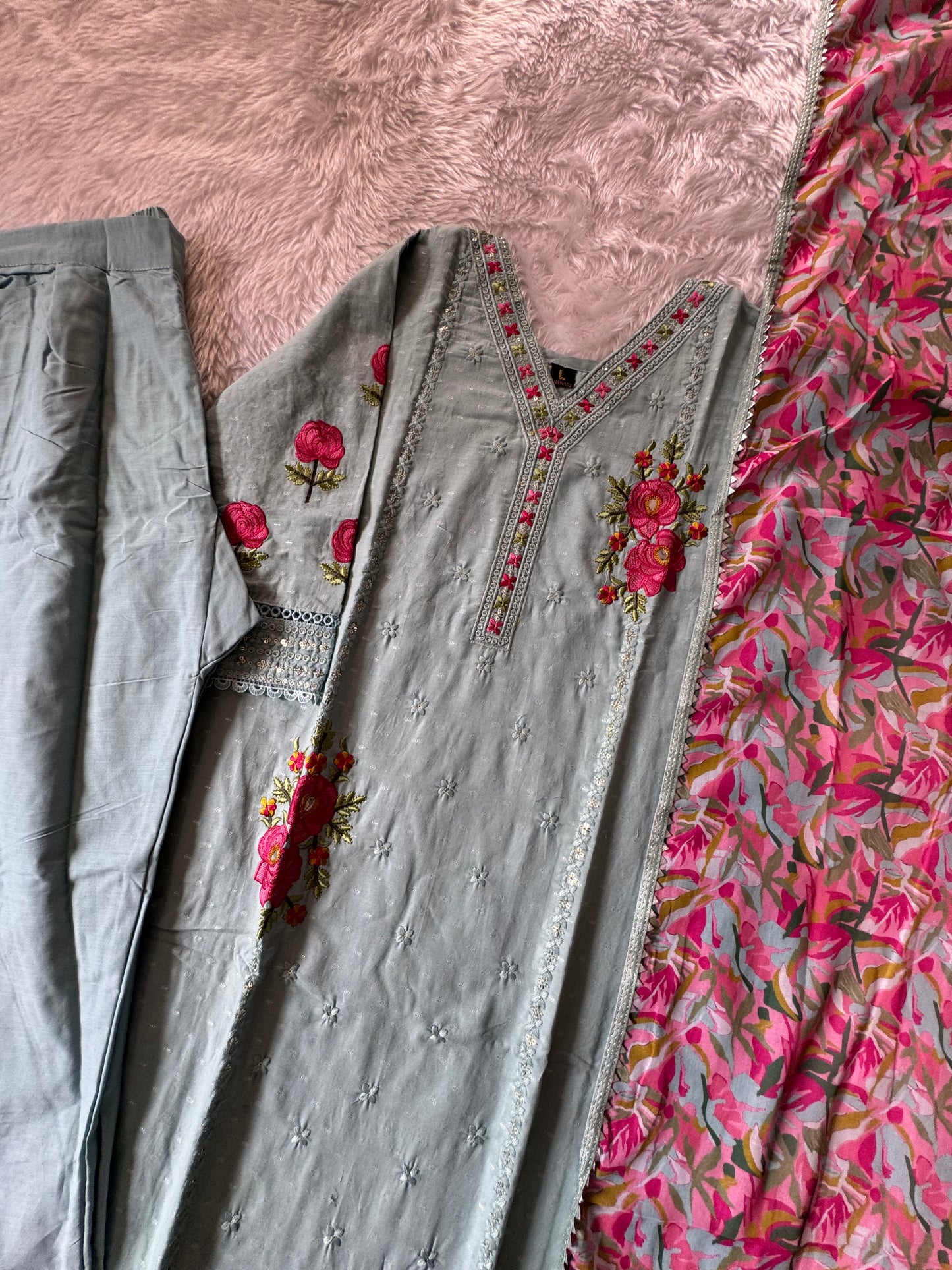 MD-178 This pastel grey suit set features delicate thread embroidery with vibrant pink floral motifs, paired with a colorful printed dupatta that adds a lively contrast. Perfect blend of subtle elegance and festive charm! ✨💗