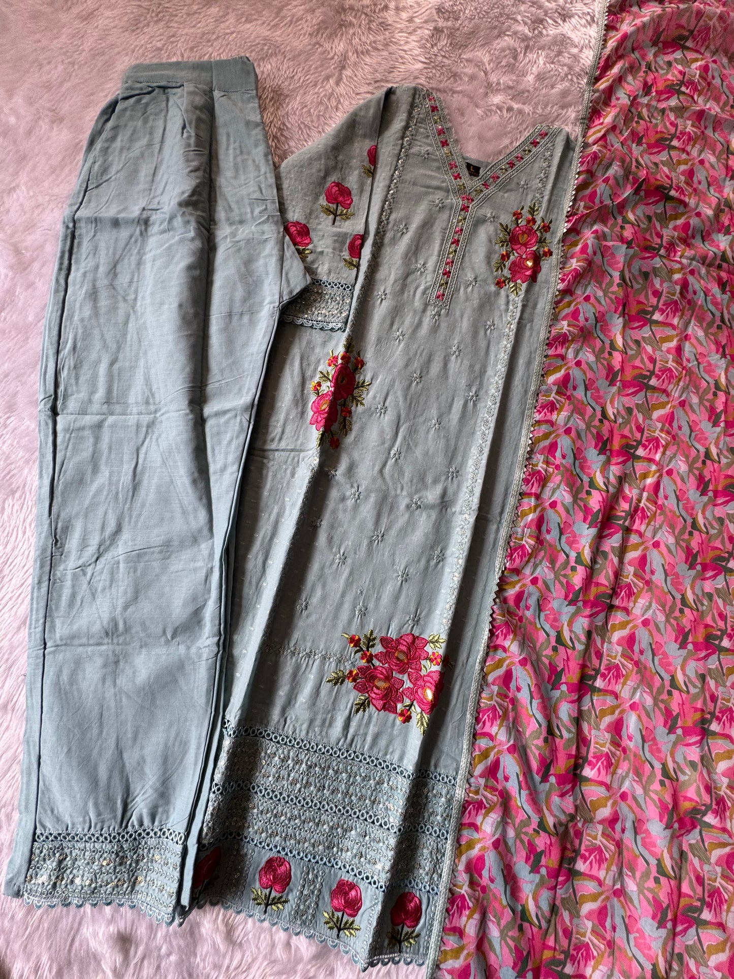 MD-178 This pastel grey suit set features delicate thread embroidery with vibrant pink floral motifs, paired with a colorful printed dupatta that adds a lively contrast. Perfect blend of subtle elegance and festive charm! ✨💗