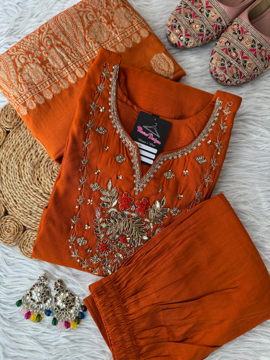 MD-189 "Embrace festive elegance in this radiant rust-orange kurta set, adorned with intricate zari embroidery and a regal Banarasi dupatta — a timeless blend of tradition and grace."