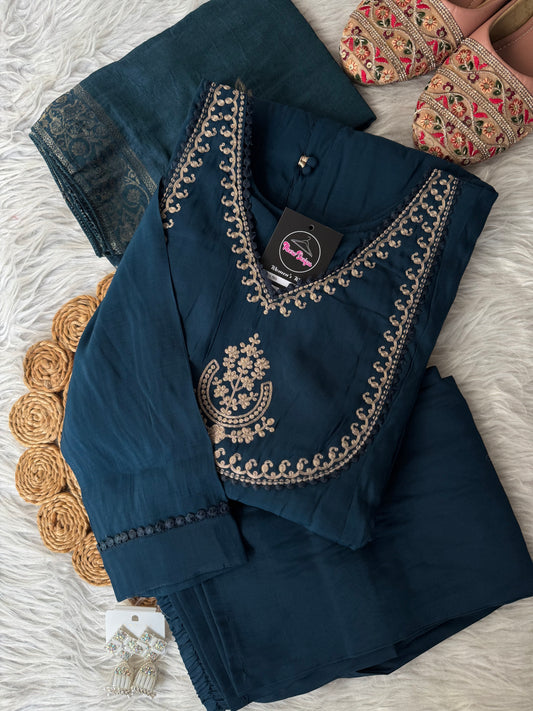MD-201 Elegant deep teal ethnic ensemble featuring a flared kurta with delicate mirror buttons and intricate golden embroidery on the neckline, paired with matching pants and a rich, woven dupatta adorned with subtle floral motifs. Perfect for festive occ