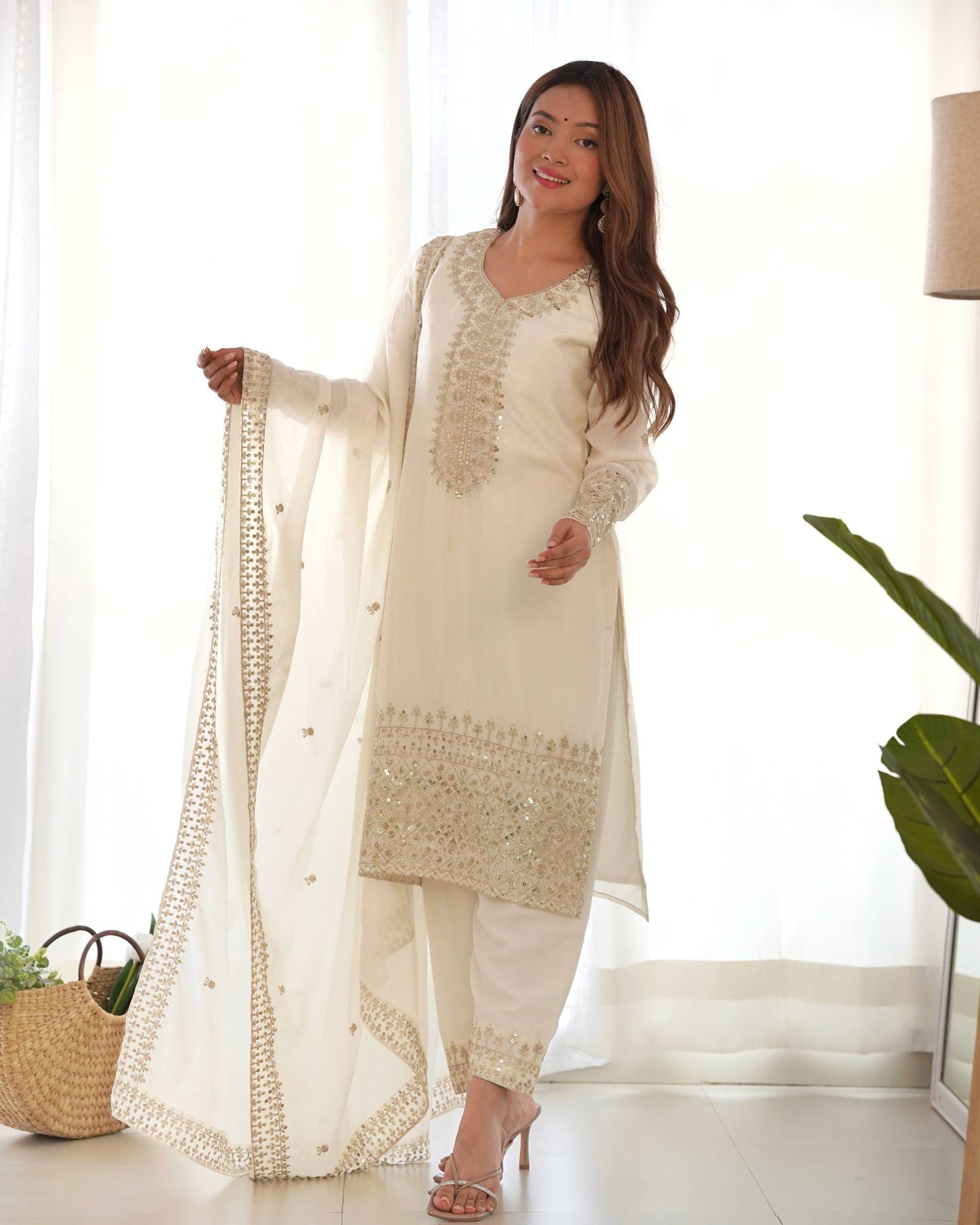 MD-245 This stunning three-piece ensemble captures the essence of sophisticated ethnic wear. Crafted in a luminous off-white silk-blend fabric, the outfit features intricate Zari and mirror-work embroidery that adds a touch of regal shimmer.