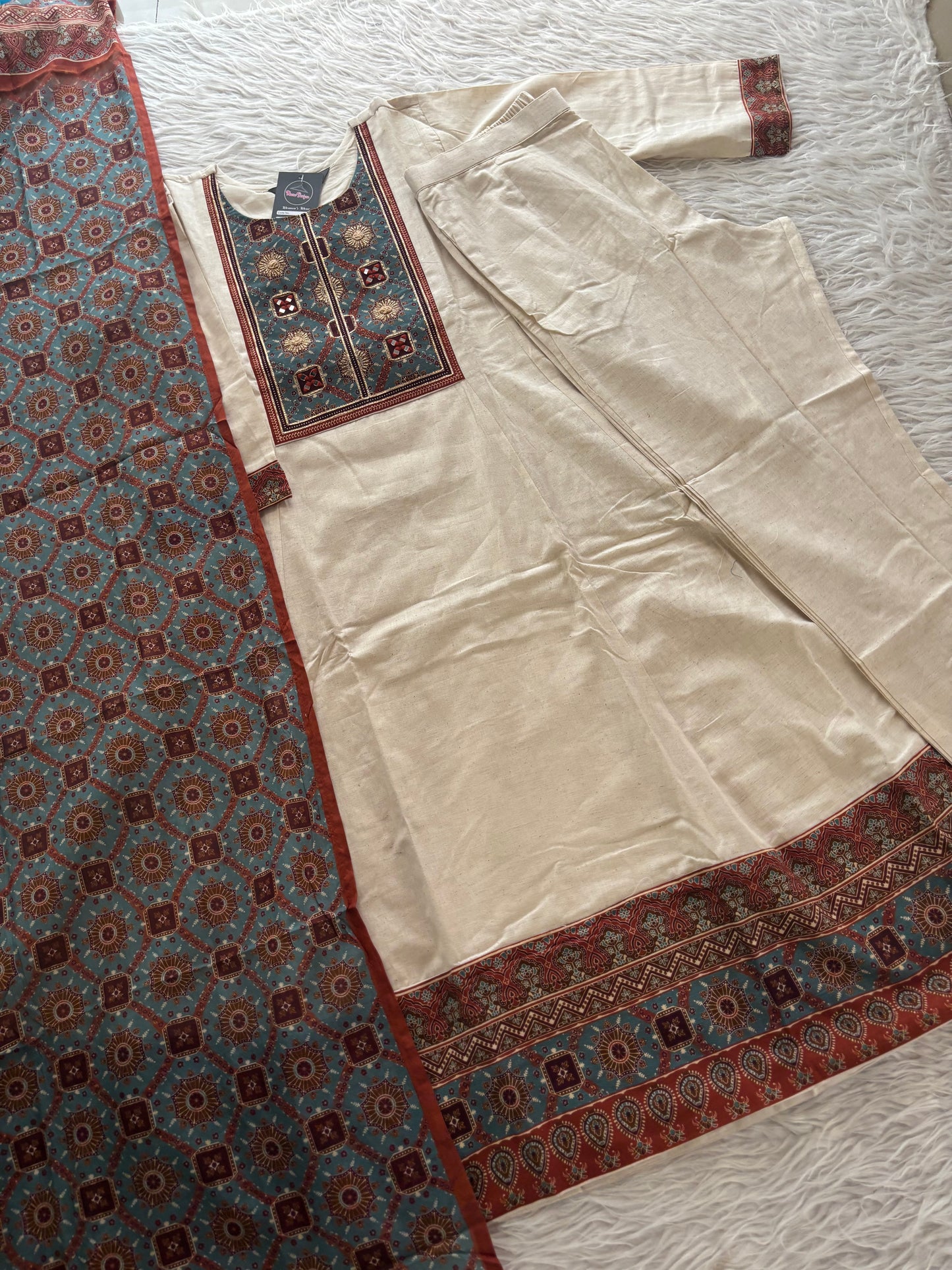 MD-247 This elegant off-white suit set features intricate ethnic embroidery and traditional motifs, perfect for a sophisticated daily look or special occasions.