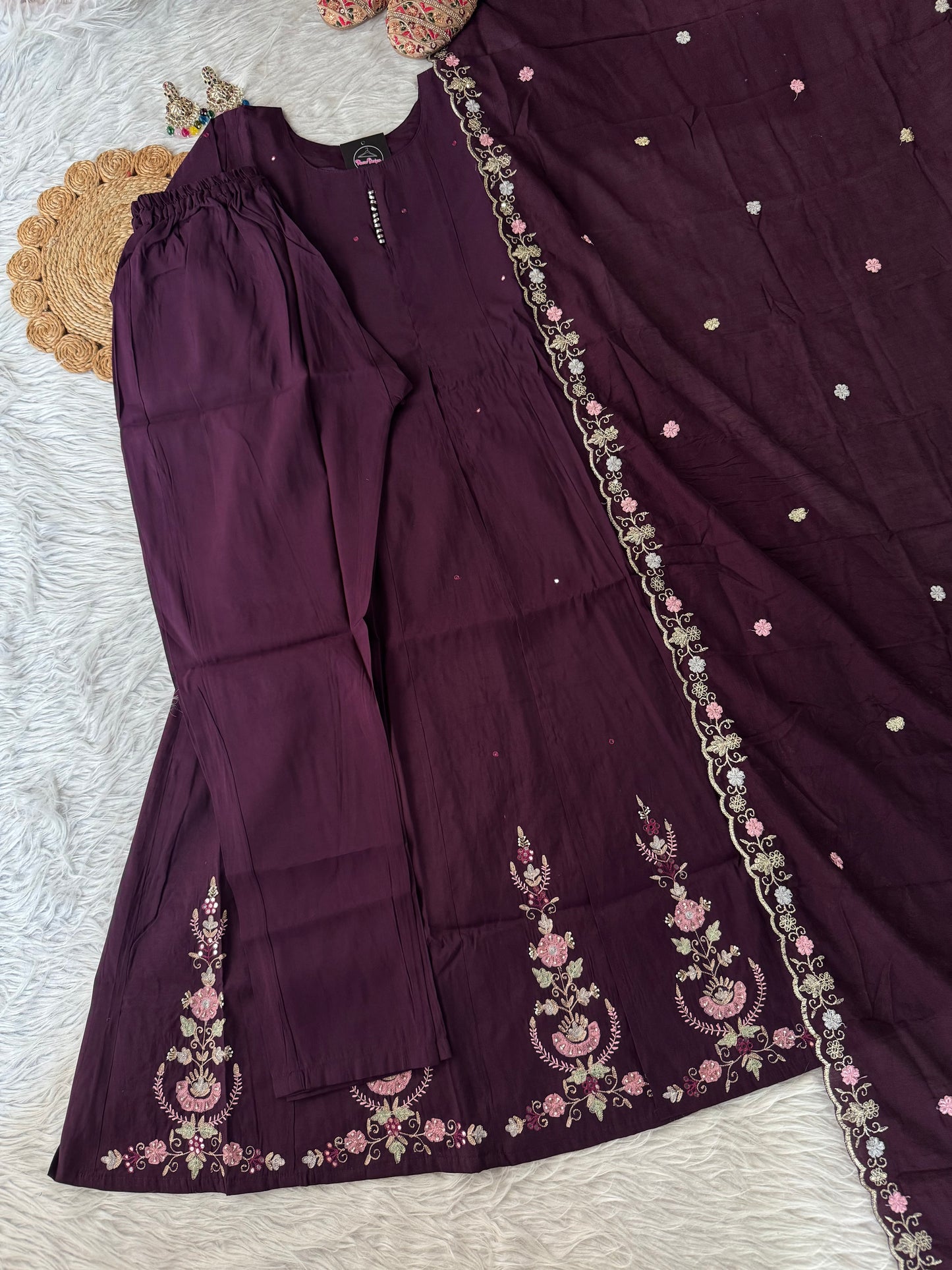 MD-194 "Unveil timeless grace in this deep plum ethnic suit, adorned with intricate floral embroidery in soft pinks and greens. Perfectly balanced between elegance and tradition, it’s a wardrobe essential for festive moments."