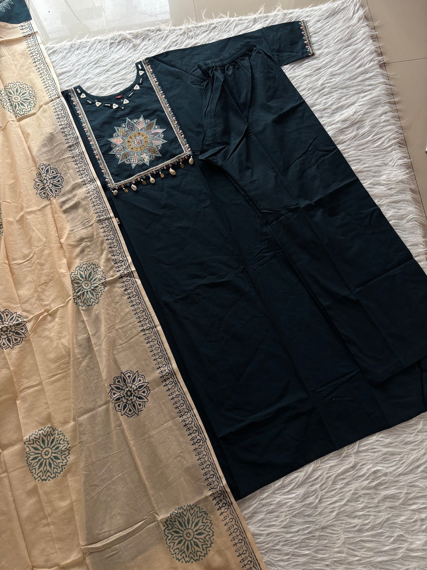 MD-265 This elegant three-piece ethnic set features a deep Kurti and matching trousers, paired with a contrasting cream-colored Dupatta. The ensemble balances rich, solid tones with intricate traditional detailing, making it ideal for festive