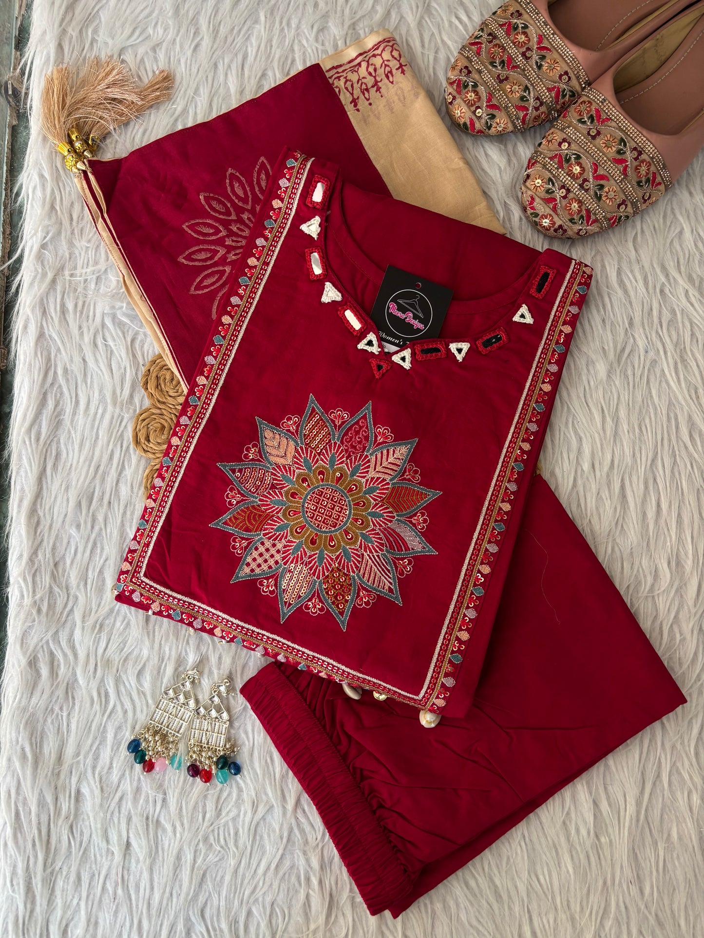 MD-265 This elegant three-piece ethnic set features a deep Kurti and matching trousers, paired with a contrasting cream-colored Dupatta. The ensemble balances rich, solid tones with intricate traditional detailing, making it ideal for festive