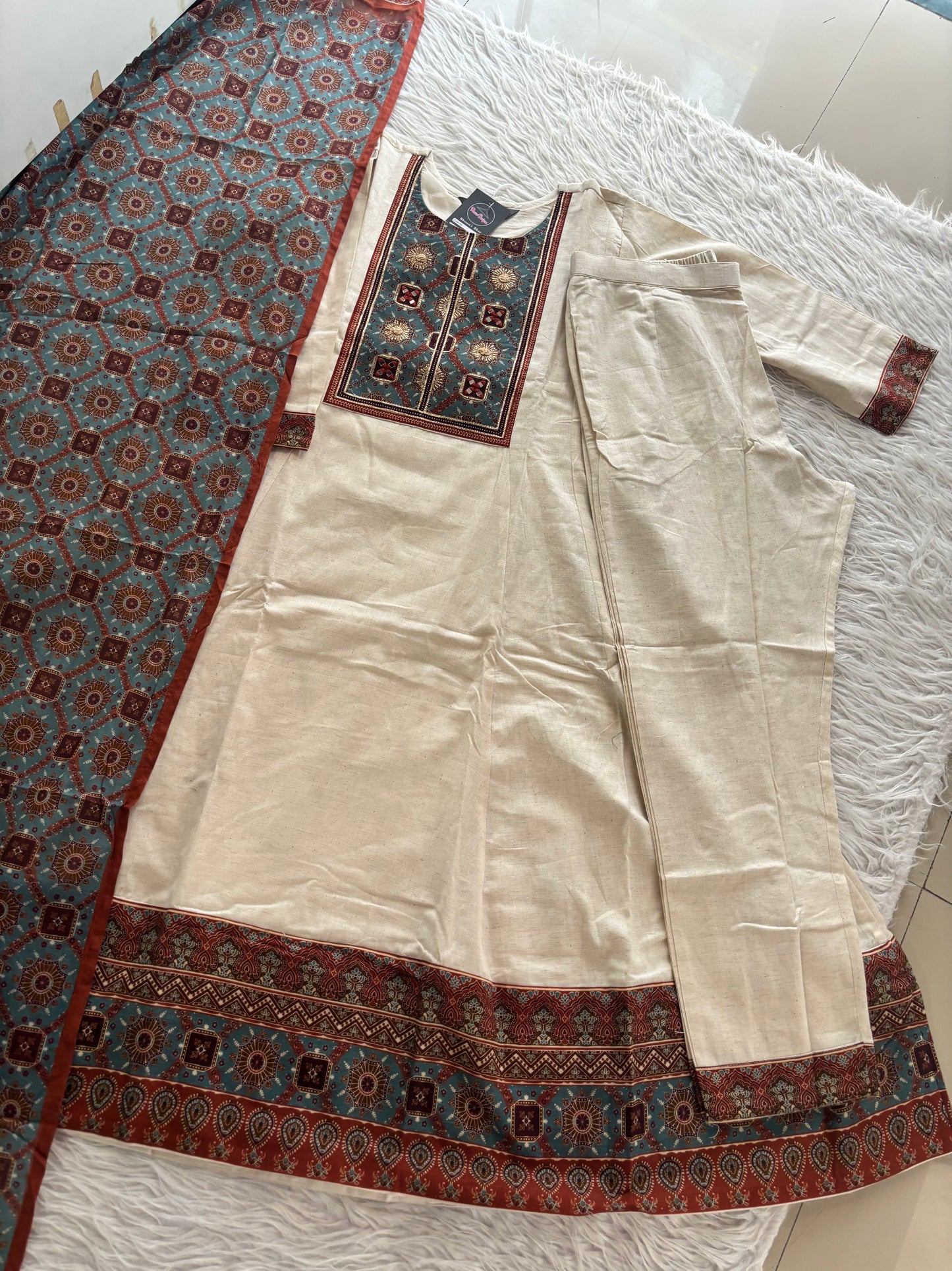 MD-247 This elegant off-white suit set features intricate ethnic embroidery and traditional motifs, perfect for a sophisticated daily look or special occasions.