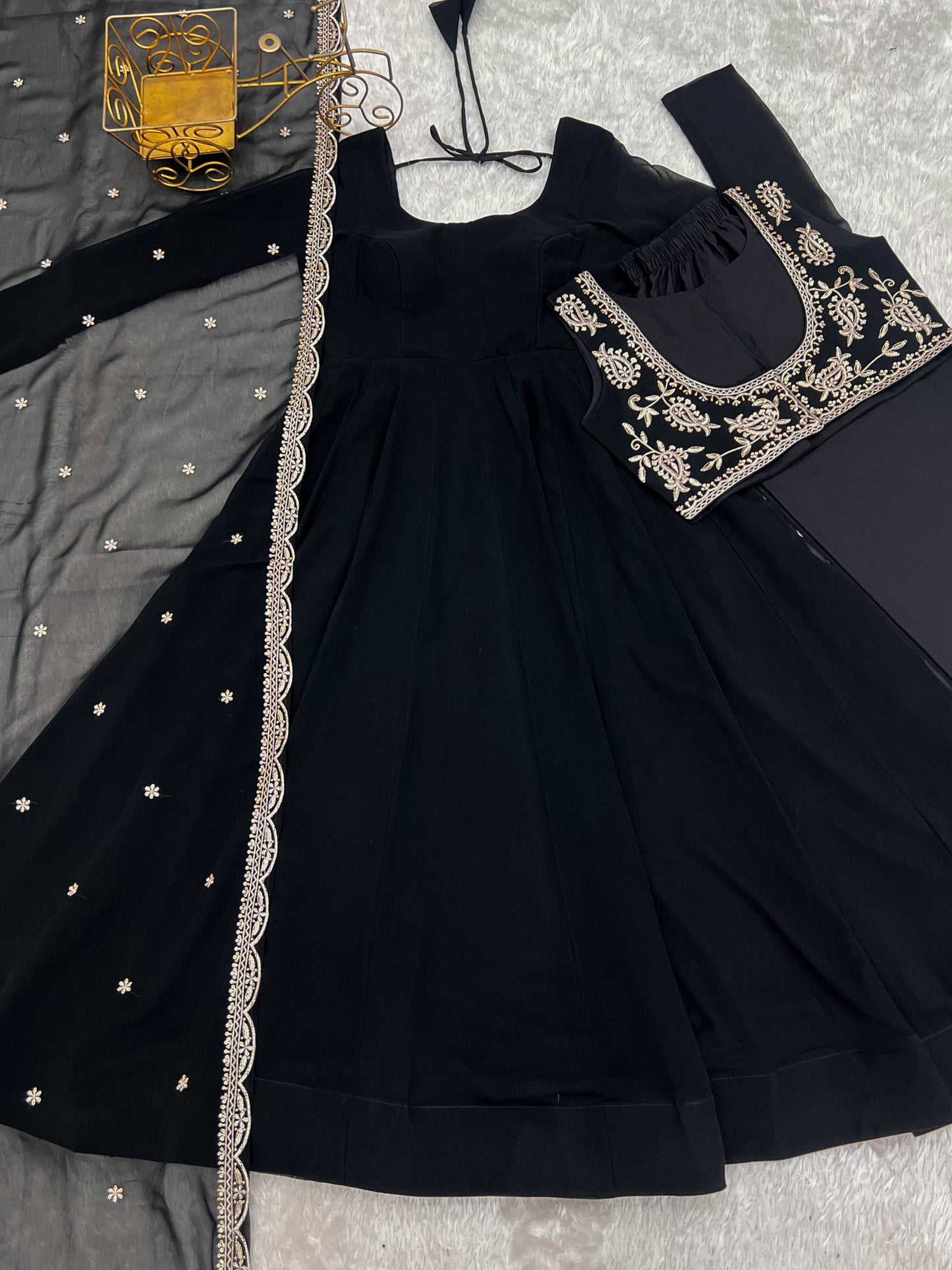 MD-242 This stunning three-piece set features a georgette Anarkali gown, designed with a graceful floor-length flare and a sophisticated round neckline. The ensemble is elevated by a matching sleeveless blouse (or jacket overlay) adorned with i