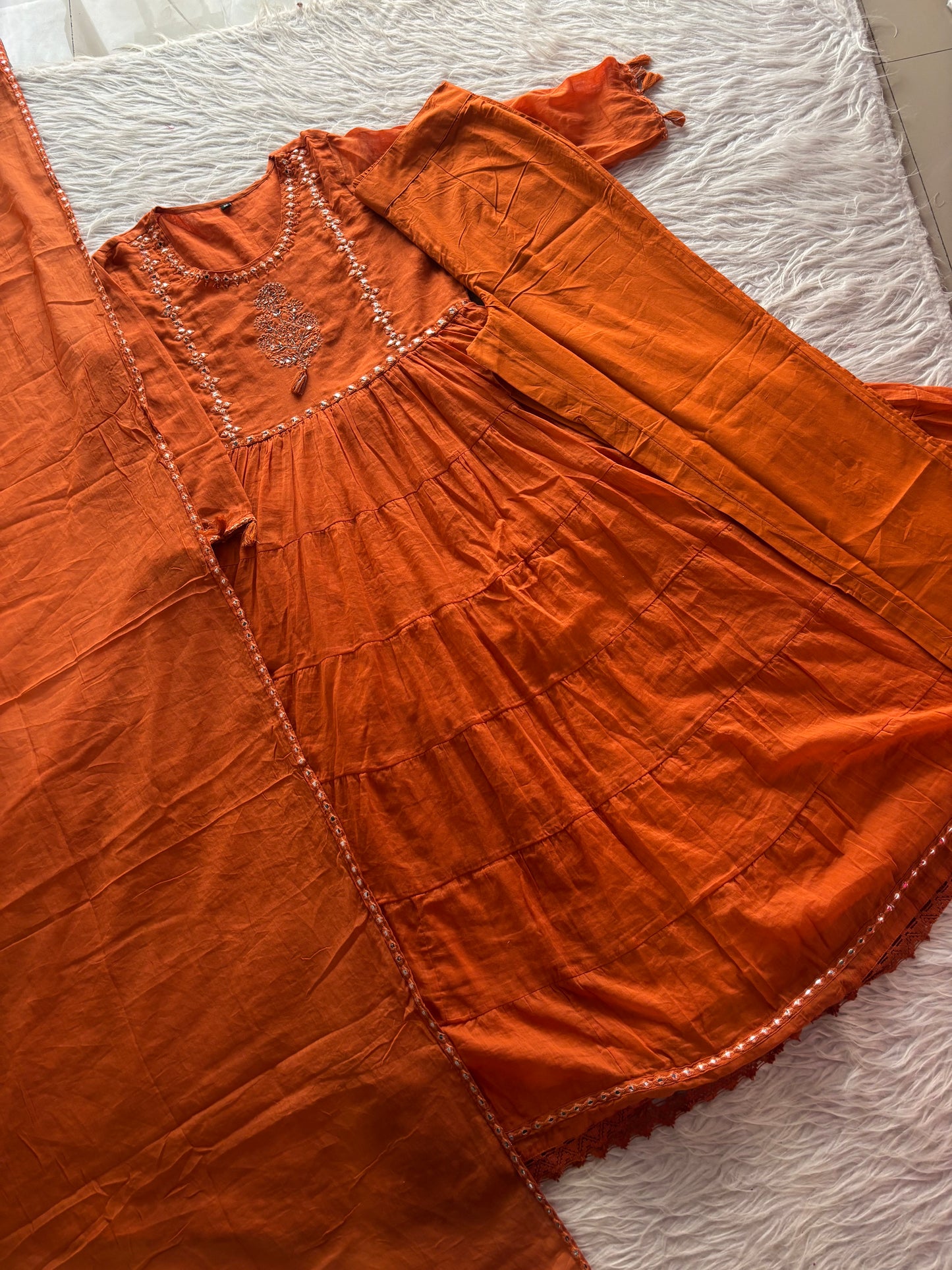 MD-262 This outfit is a vibrant tiered Anarkali suit set, likely crafted from a breathable cotton or cotton-slub fabric. It blends traditional Indian ethnic wear with a modern, breezy silhouette.