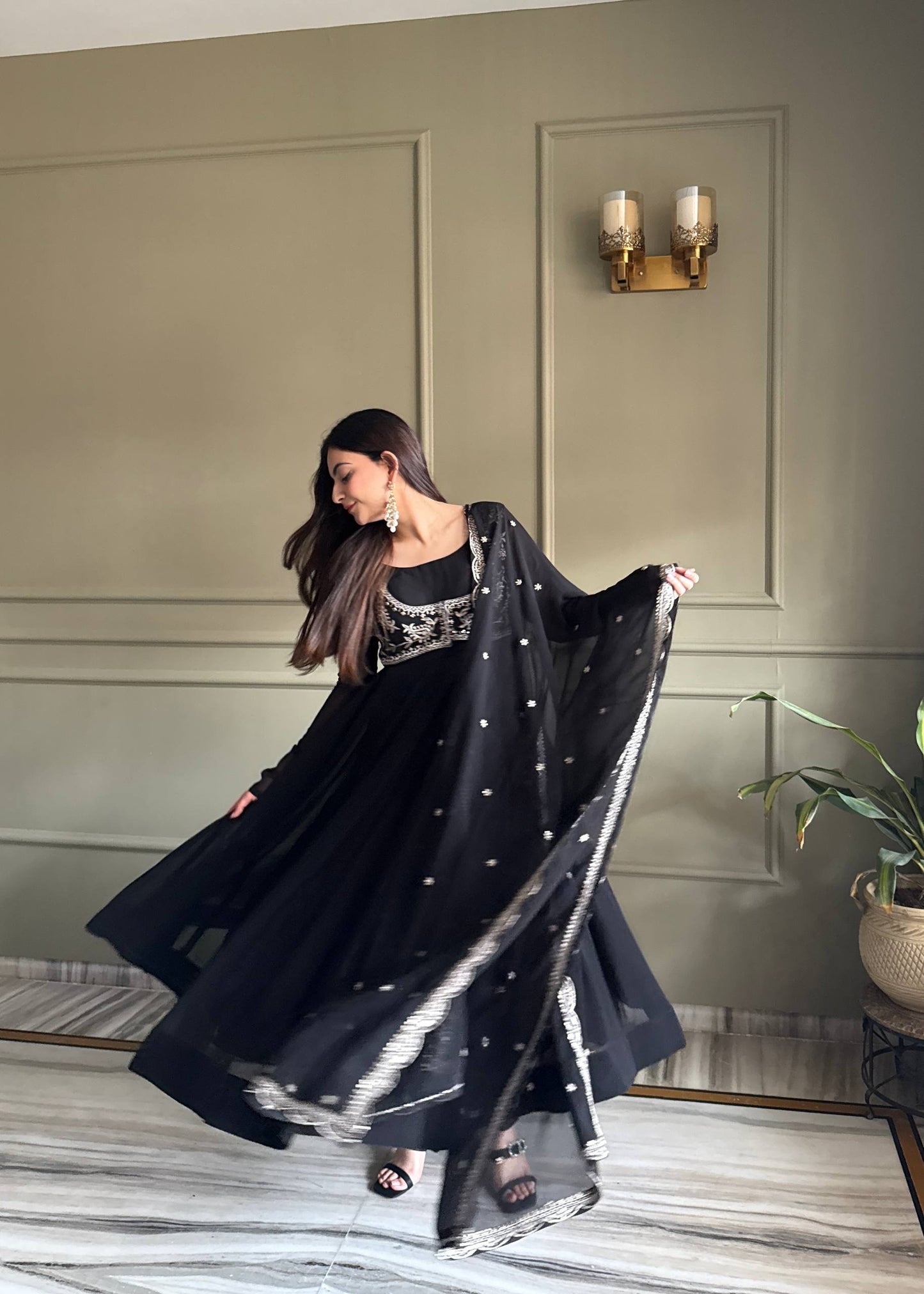 MD-242 This stunning three-piece set features a georgette Anarkali gown, designed with a graceful floor-length flare and a sophisticated round neckline. The ensemble is elevated by a matching sleeveless blouse (or jacket overlay) adorned with i