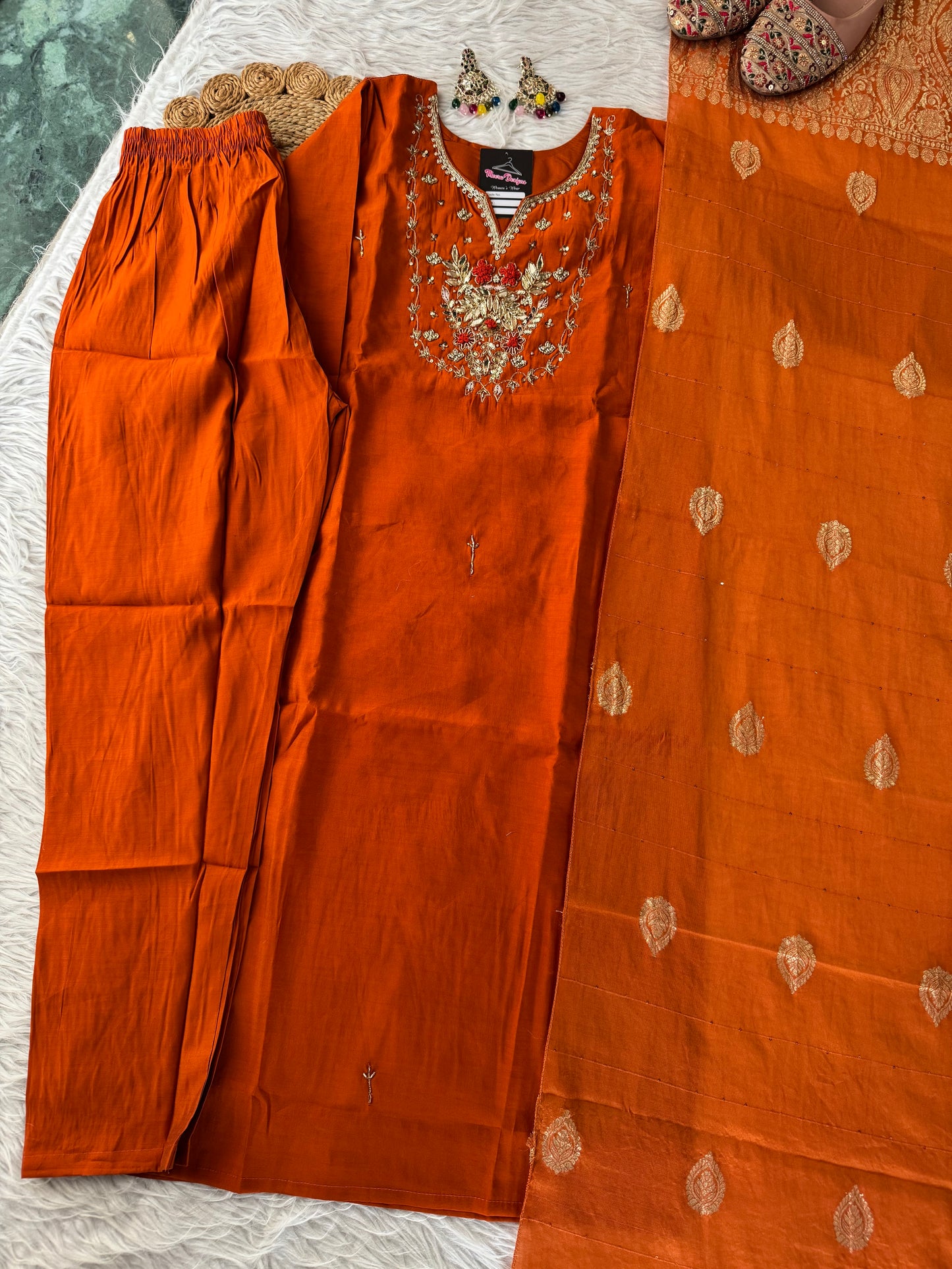MD-189 "Embrace festive elegance in this radiant rust-orange kurta set, adorned with intricate zari embroidery and a regal Banarasi dupatta — a timeless blend of tradition and grace."