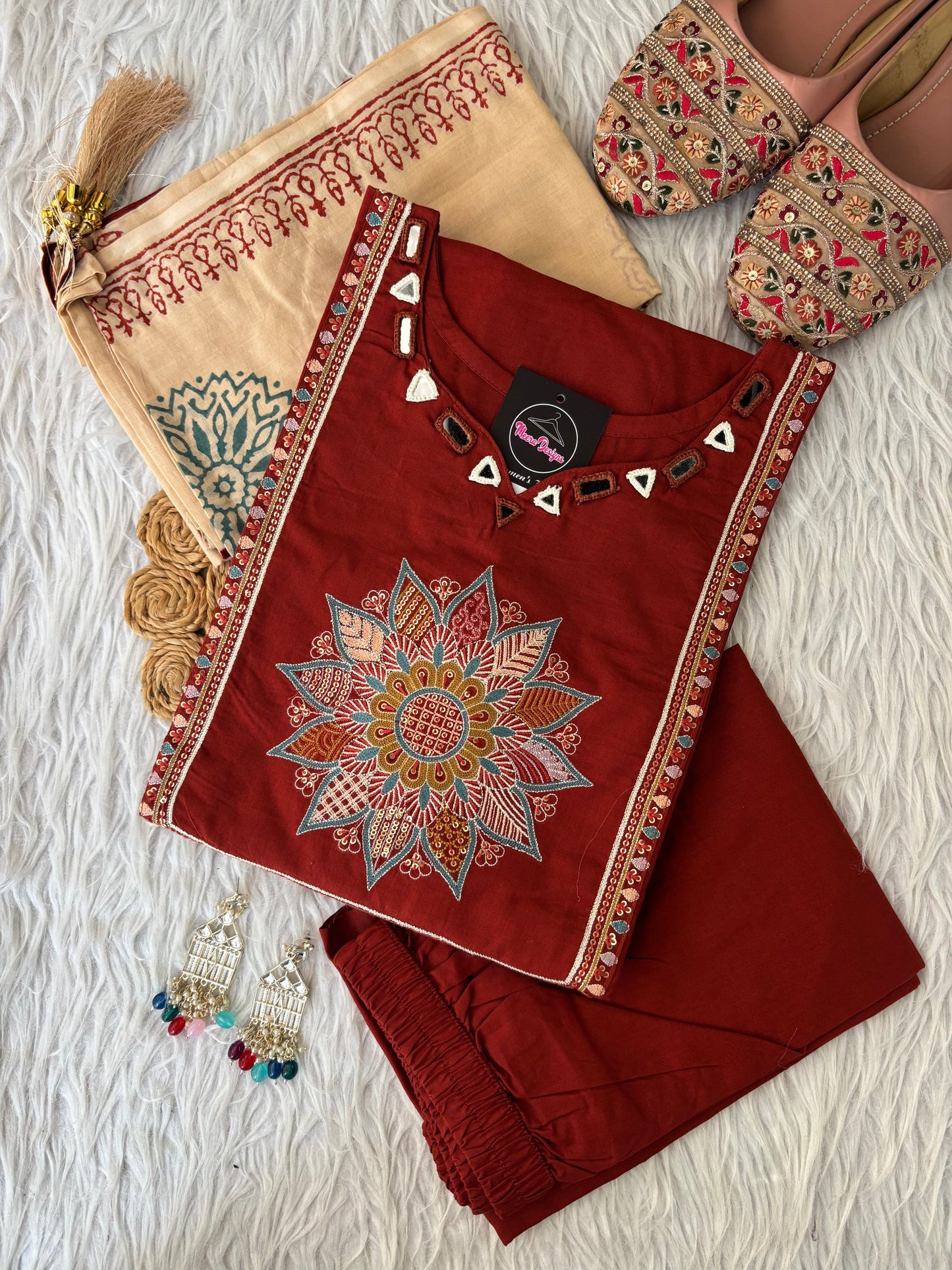 MD-265 This elegant three-piece ethnic set features a deep Kurti and matching trousers, paired with a contrasting cream-colored Dupatta. The ensemble balances rich, solid tones with intricate traditional detailing, making it ideal for festive