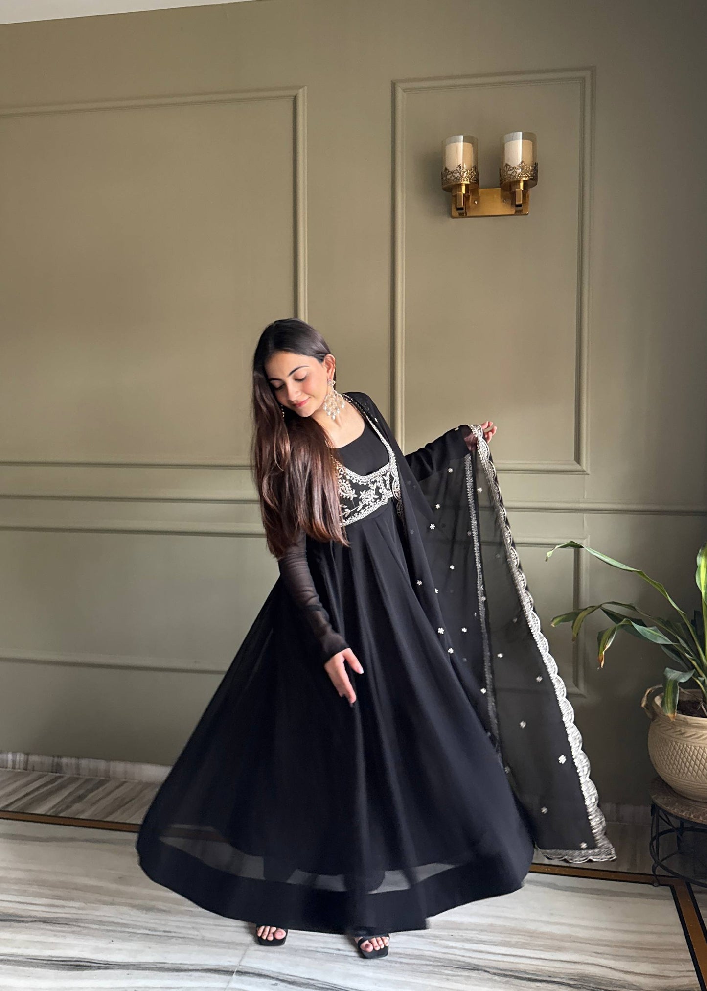 MD-242 This stunning three-piece set features a georgette Anarkali gown, designed with a graceful floor-length flare and a sophisticated round neckline. The ensemble is elevated by a matching sleeveless blouse (or jacket overlay) adorned with i