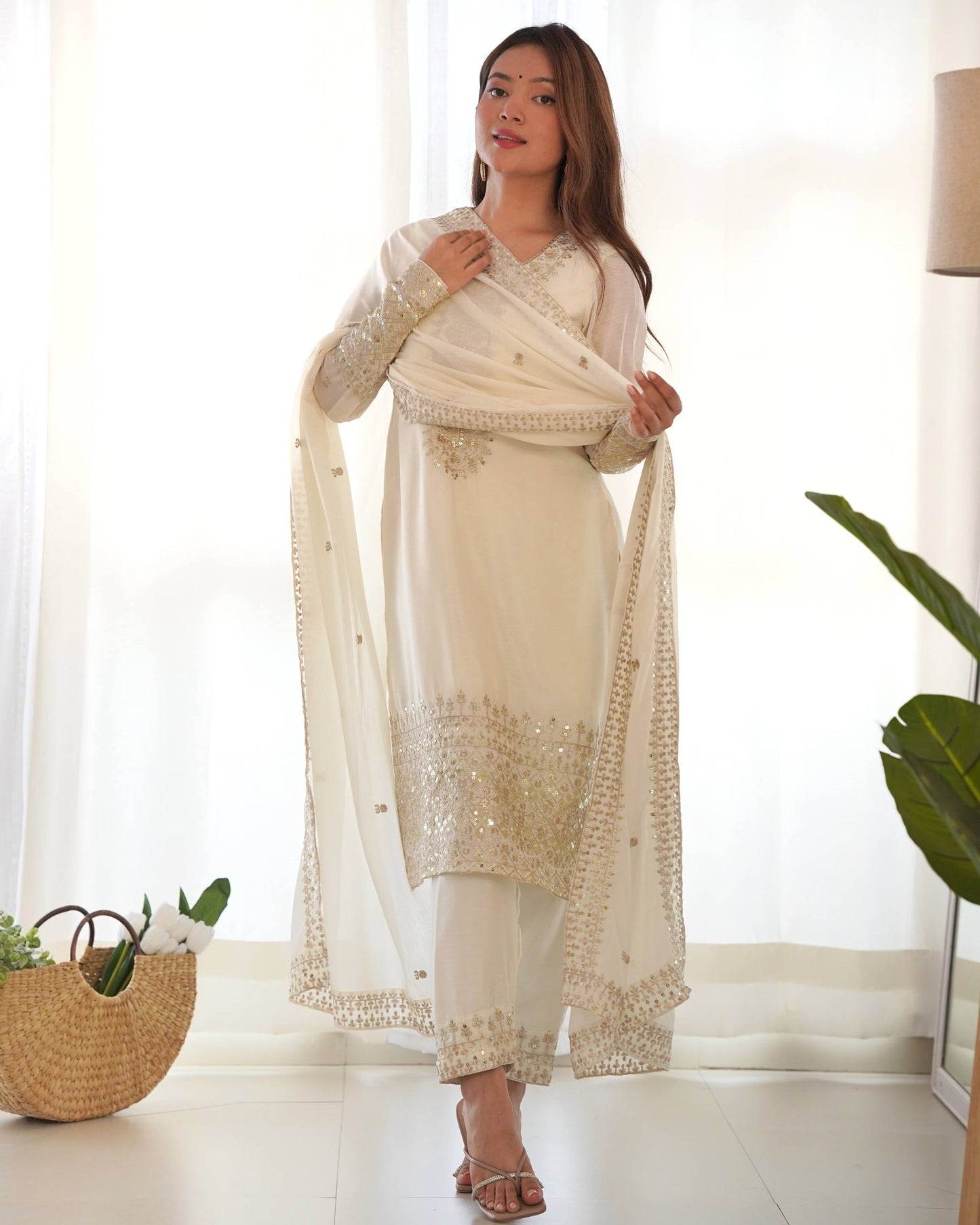 MD-245 This stunning three-piece ensemble captures the essence of sophisticated ethnic wear. Crafted in a luminous off-white silk-blend fabric, the outfit features intricate Zari and mirror-work embroidery that adds a touch of regal shimmer.